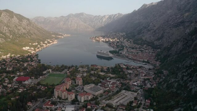 Aerial panoramic video of the picturesque bay of Kotor (Boka Kotor) with beautiful coastline, red roofs, marina with boats and big cruise ship, Montenegro.