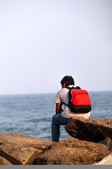 the lonely man sitting on a stone near an ocean