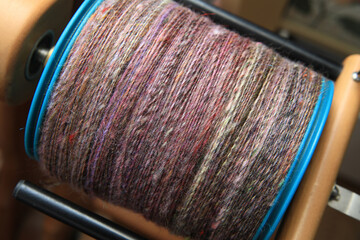 Closeup detail of a bobbin full of colourful organic natural handspun and handdyed merino sheep...