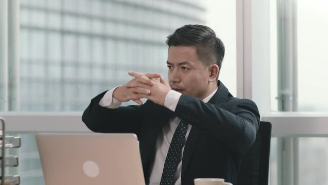 asian business manager laying back in chair thinking in modern office