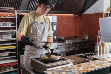 Professional Chef preparing cheesecakes on frying pan for breakfast in restaurant kitchen