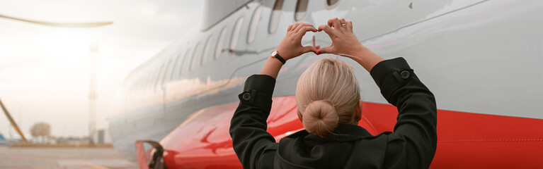 Back view of flight attendant looking on aircraft and showing sign heart