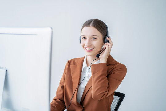 Friendly smiling female call-center agent with headset working on support hotline in office.
