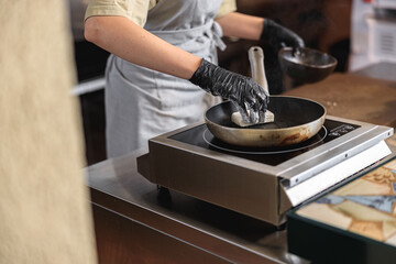 The chef breads the cheese in flour before frying it in a pan in restaurant kitchen