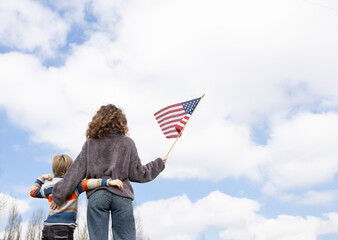 unrecognizable boy and young woman stand together with their backs holding american flag against sky. Freedom, national identity. Independence Day of the United States of America. Travel, immigration