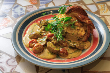 Tasty croissant filled with omelet with fried vegetables and sauce served on plate for breakfast