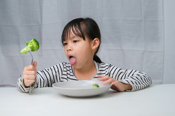 Children don't like to eat vegetables. Cute Asian girl refusing to eat healthy vegetables....