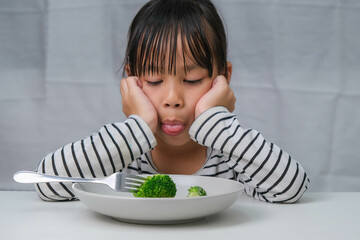 Children don't like to eat vegetables. Cute Asian girl refusing to eat healthy vegetables....
