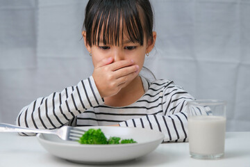 Children don't like to eat vegetables. Cute Asian girl refusing to eat healthy vegetables....
