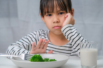 Children don't like to eat vegetables. Cute Asian girl refusing to eat healthy vegetables....