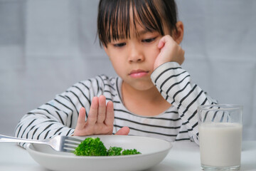 Children don't like to eat vegetables. Cute Asian girl refusing to eat healthy vegetables....