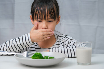 Children don't like to eat vegetables. Cute Asian girl refusing to eat healthy vegetables....