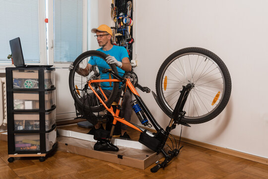 Young man watching online manual how to repair broken bicycle at home