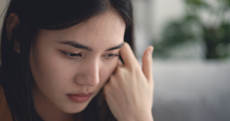 Young asian woman sitting on sofa so thoughtful and sadness in living room