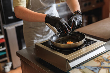 Chef break an egg on a frying pan to make delicious breakfast. Working environment in the kitchen 