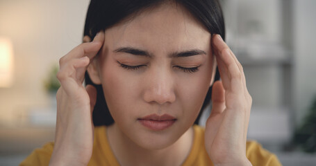 Fototapeta premium Young asian woman sitting on sofa headache on sofa in living room