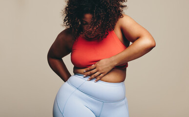 Embracing every curve, sporty woman looks at her body in a studio