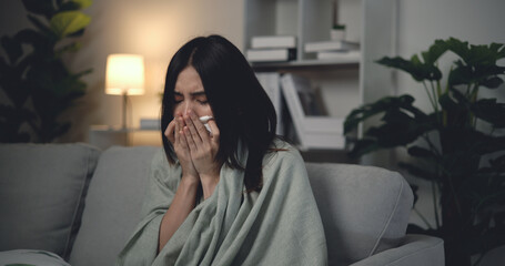 Asian Young woman sitting under blanket with sneezing and flu at home
