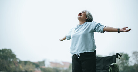 Asian mature woman feeling proud of her efforts to stand up from her wheelchair