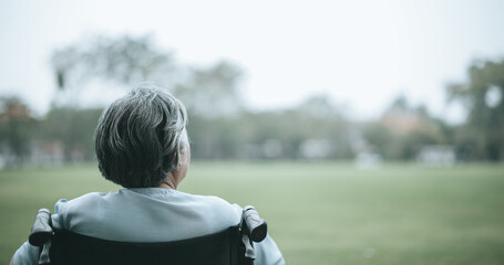 Fototapeta premium Mature Asian woman sitting on wheelchair relaxing in park