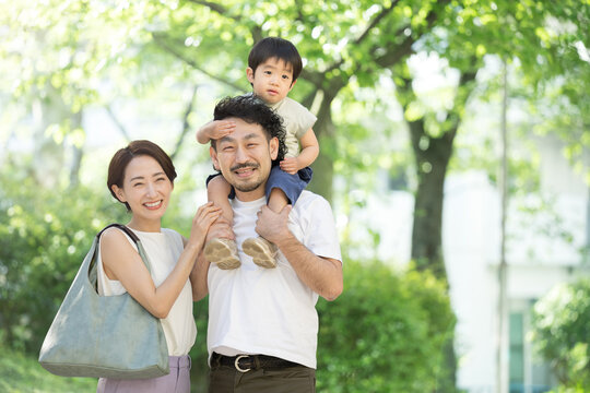A family of good friends riding on each other's shoulders amidst fresh greenery and foliage, spring and summer image with copyspace on the right, close-up.