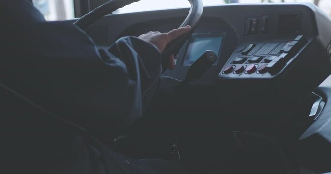 Close up of male hands. The driver is sitting at steering wheel of a bus