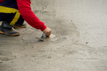Hand builder with trowel leveling concrete, spreading poured. Some motion blur present. For...