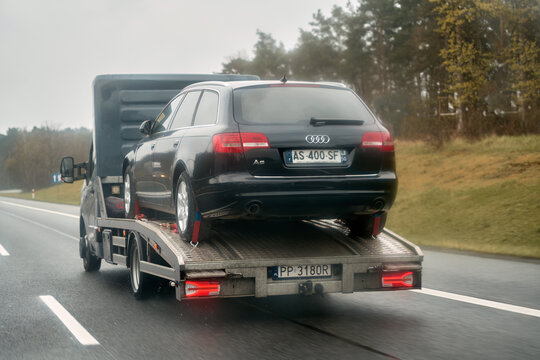 15.04.2023 Europe, Germany. Tow truck with broken car on country road. Tow truck transporting car on the highway. Car service transportation concept.
