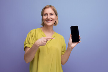 cheerful blond middle-aged woman joyfully masters gadget including smartphone