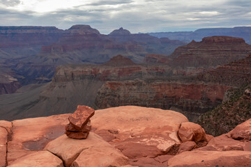 Big stone with panoramic aerial view from South Kaibab hiking trail at South Rim of Grand Canyon National Park, Arizona, USA, America. Colorado River weaving through valleys and rugged terrain. Clouds