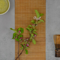 Green twig witch flowers, matcha tea, bamboo broom and bamboo mat in oriental style, flat lay.
