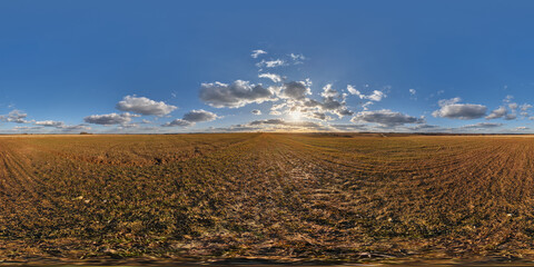 spherical 360 hdri panorama among farming field with clouds and sun on evening blue sky before...