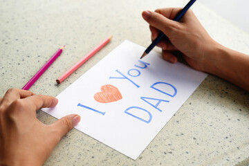 Hand writing on a paper card, I Love You Dad, preparing Father's Day card.