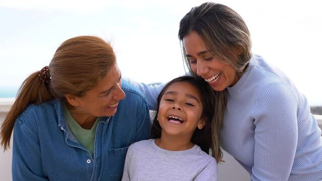 Happy multigenerational latin family having tender moment in front of camera - Grandmother, daughter and granddaughter love concept
