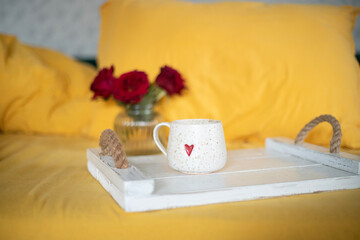 A cup of warm, warming aromatic tea, coffee, flowers nearby