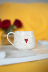 A cup of warm, warming aromatic tea, coffee, flowers nearby