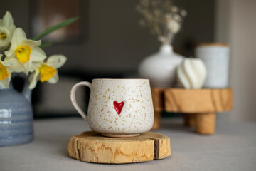 A cup of warm, warming aromatic tea, coffee, flowers nearby