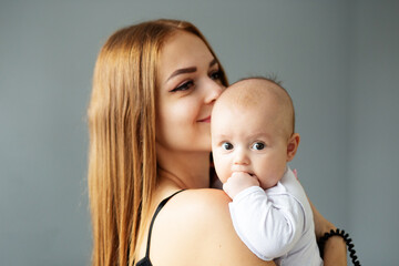 Mother takes care of newborn baby at home. Smiling mother holds two month old daughter in arms. Kiss