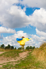 little girl in national Ukrainian clothes - vyshyvanka. Ukraine, field. In the hands of the flag of Ukraine.	
