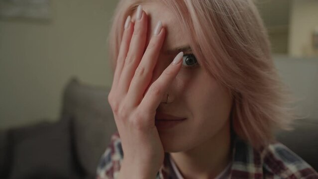 Woman Makes Face Palm Gesture Close Up. Female expressing disbelief, exasperation, shame, irritation or annoyance sitting on couch at home. Handheld Camera.