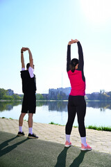 The stunning photo captures a young couple as they warm up, stretch and train near the serene lake....