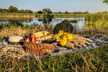 Picnic basket with food and cider wine bottle near the water