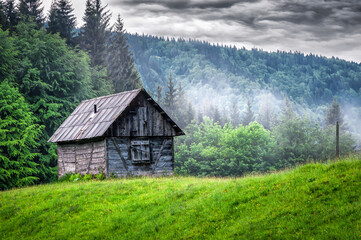 Wooden abandoned cabin in rainy mountains