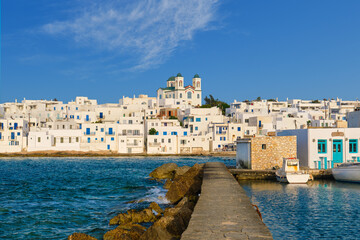 Fototapeta na wymiar Greek whitewashed houses and church by harbour watersfront on sunny