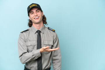 Young safeguard man isolated on blue background presenting an idea while looking smiling towards