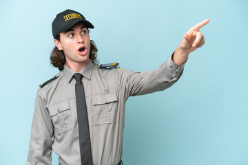 Young safeguard man isolated on blue background pointing away