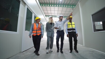 Group of factory warehouse workers walking and talking in warehouse for work wearing safety hardhats helmet inspection at warehouse