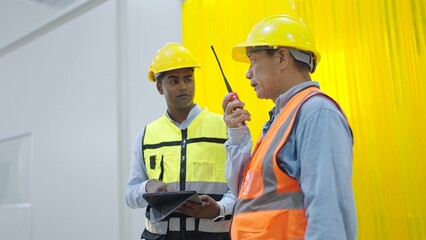 Two professional factory warehouse workers holding tablet and radio communication talking and disussing for work in factory