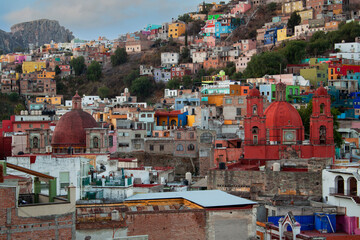 Exterior view of colorful historical old town buildings, and towers of a red church in downtown Guanajuato state, Mexico. Vivid, multicolored colonial neighborhood, traditional Mexican architecture.
