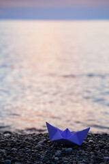 paper boat by the sea at sunset